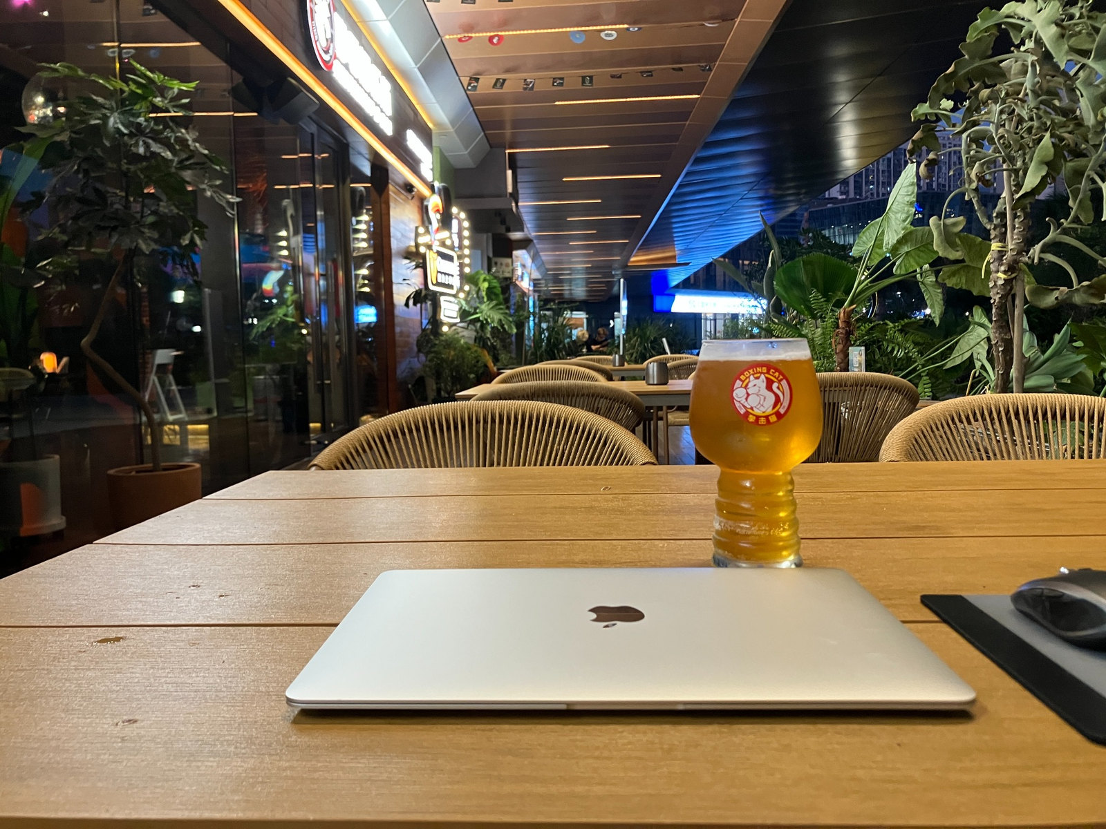 テラス席の木製テーブルに置かれたグラスとMacBook